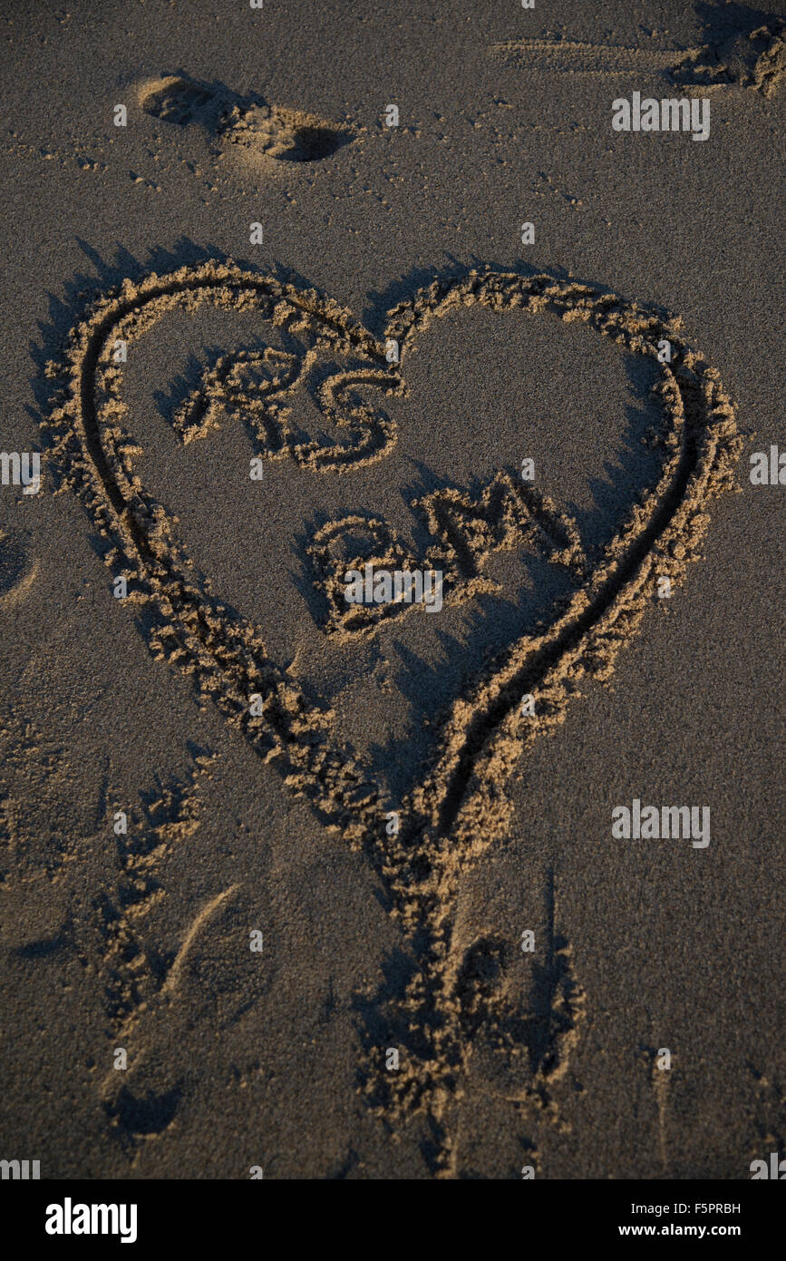 Un cuore disegnato in sabbia con due nomi in essa Foto Stock