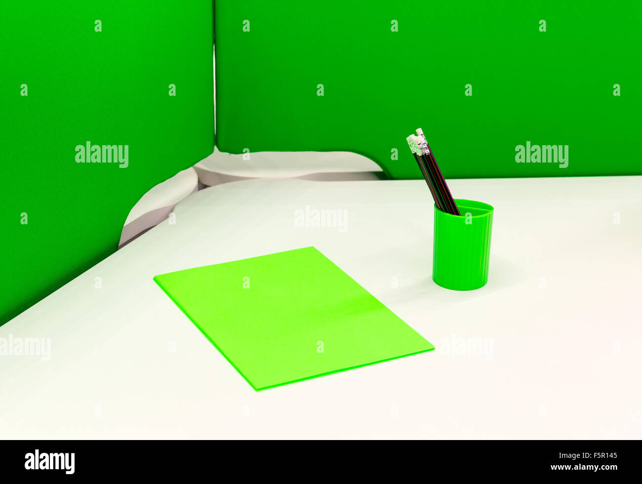 Foglio verde della carta e pennarelli in un contenitore verde Foto Stock