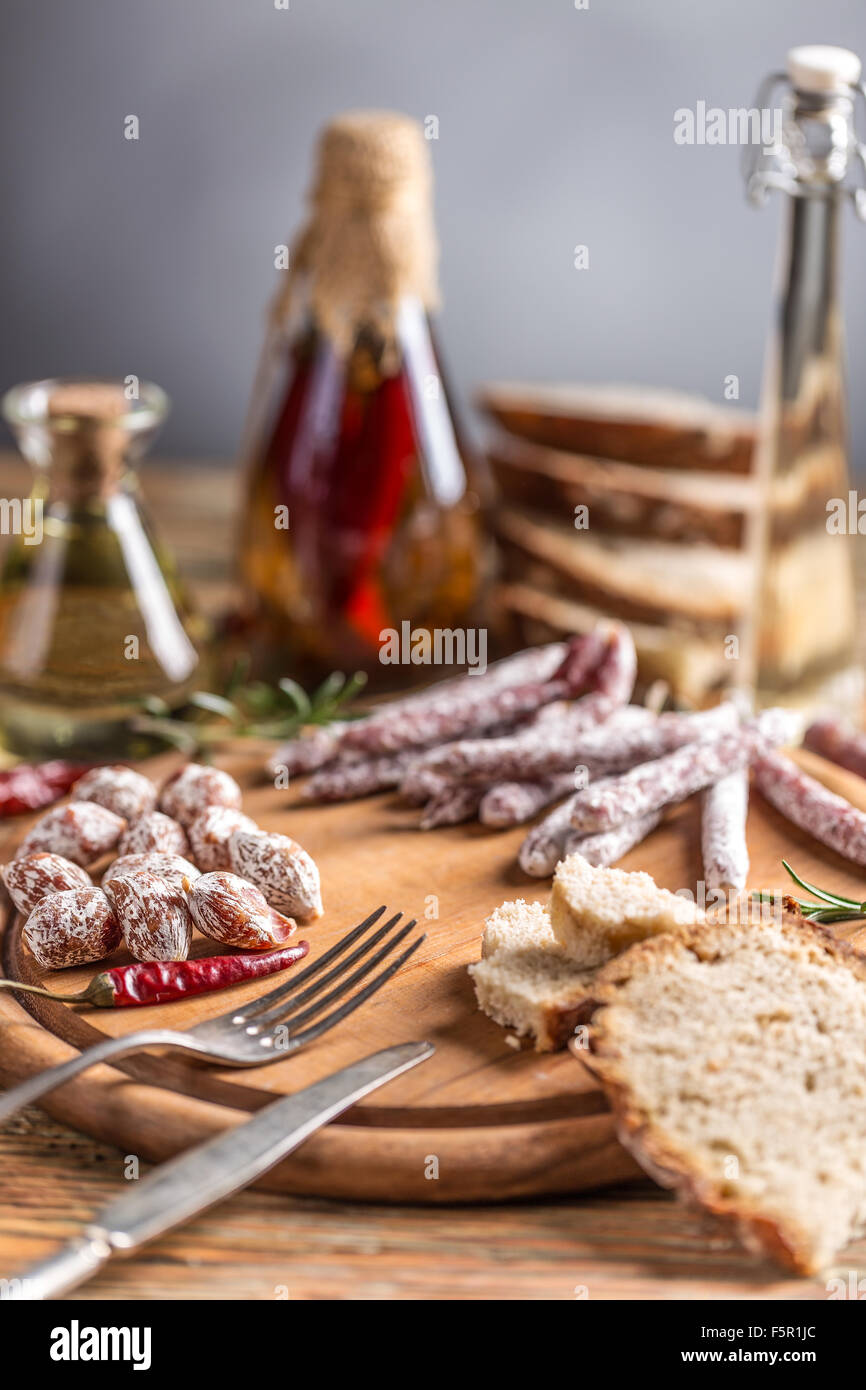 Set di salame salumi serviti con red hot chili peppers sul tagliere di legno Foto Stock
