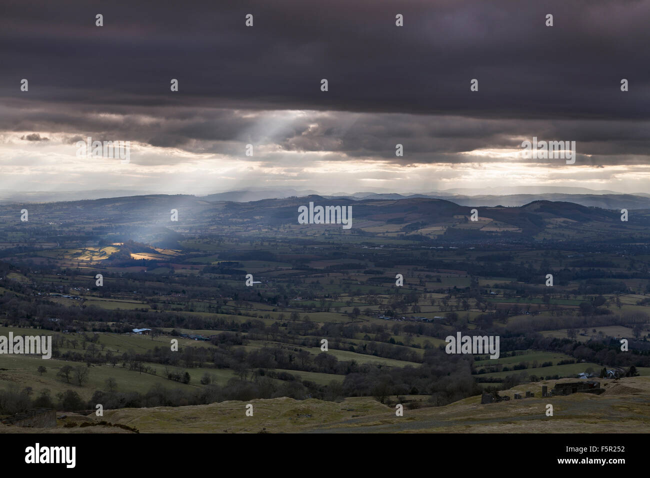 Raggi crepuscolari rompere attraverso le nuvole di illuminazione campi attraverso Shropshire, da Clee Hill guardando verso il Galles Foto Stock
