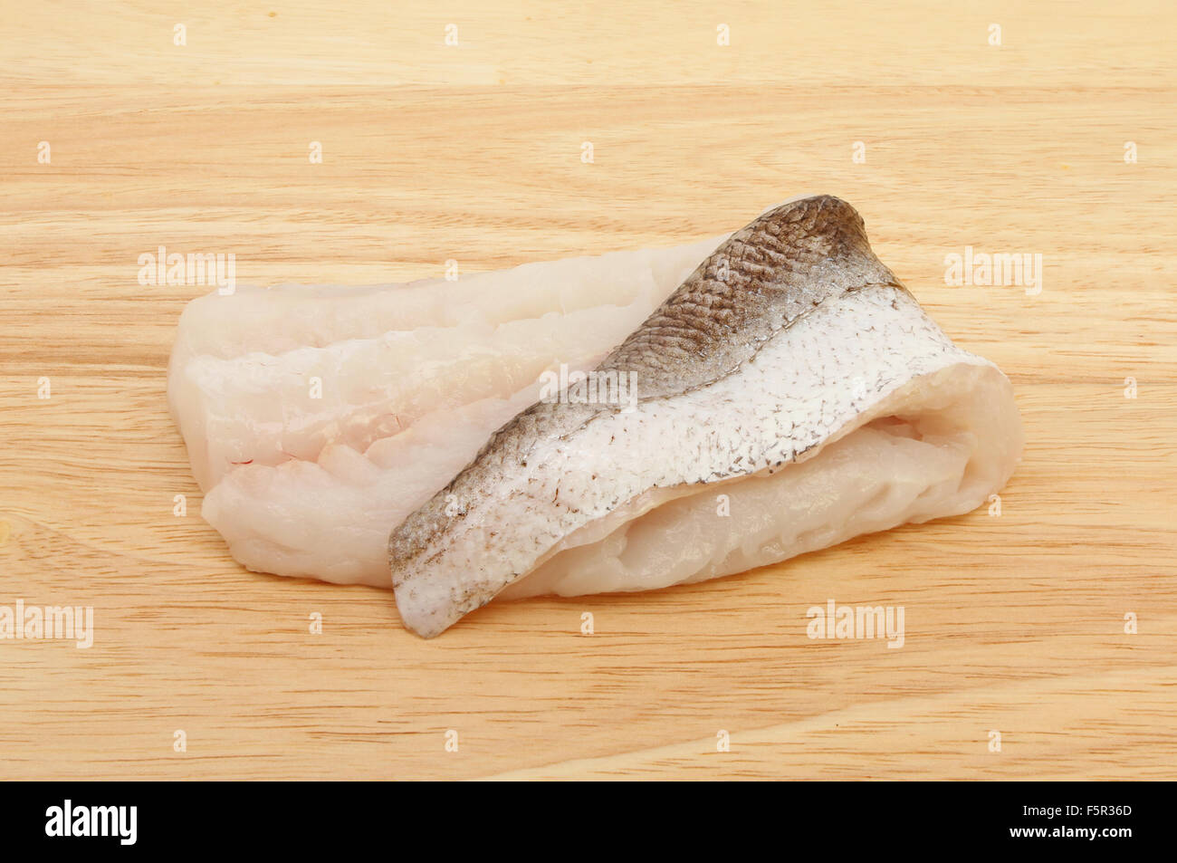 Nasello crudo filetto di pesce su una tavola di legno Foto Stock