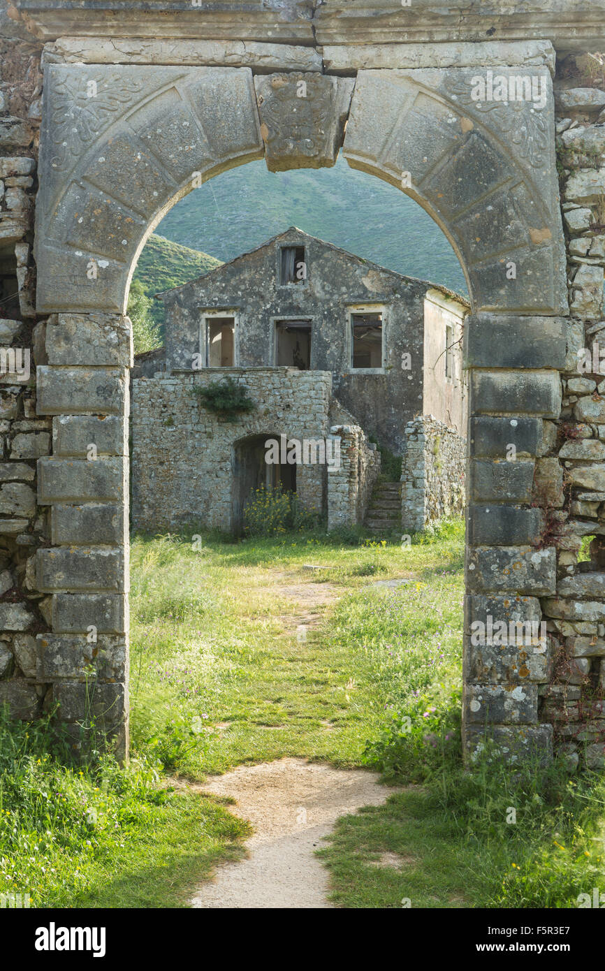 Un antico arco in PALIÀ PERITHIA, Palaia Peritheia, Corfù, Grecia, con un edificio abbandonato in background. Foto Stock