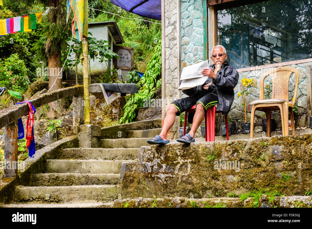 Il vecchio uomo seduto su una sedia accanto a gradino con giornali e spazio di copia Foto Stock