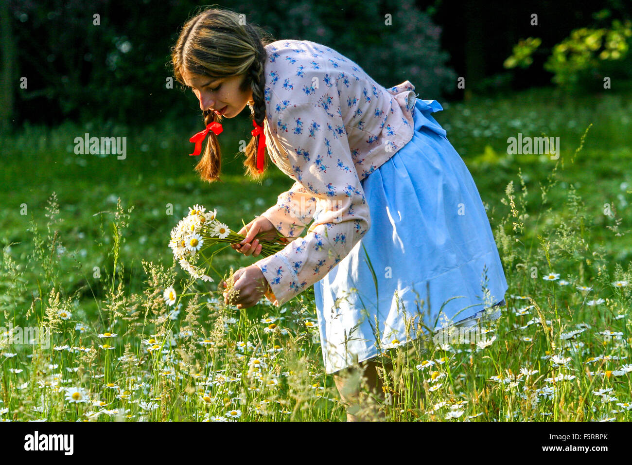 Giovane donna succhia Daisies ragazza che succhia i fiori nel costume tradizionale Folk Meadow Moravia Repubblica Ceca vestito Folk femminile una persona vestito Foto Stock