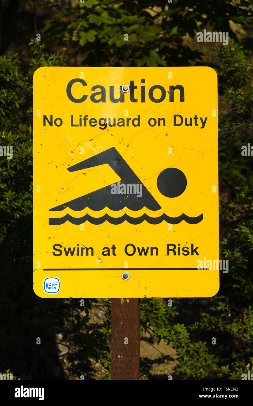 Segno "Attenzione, niente bagnino di turno, nuotare a proprio rischio e pericolo'. Lago Okanagan Parco Provinciale, British Columbia, Canada. Foto Stock