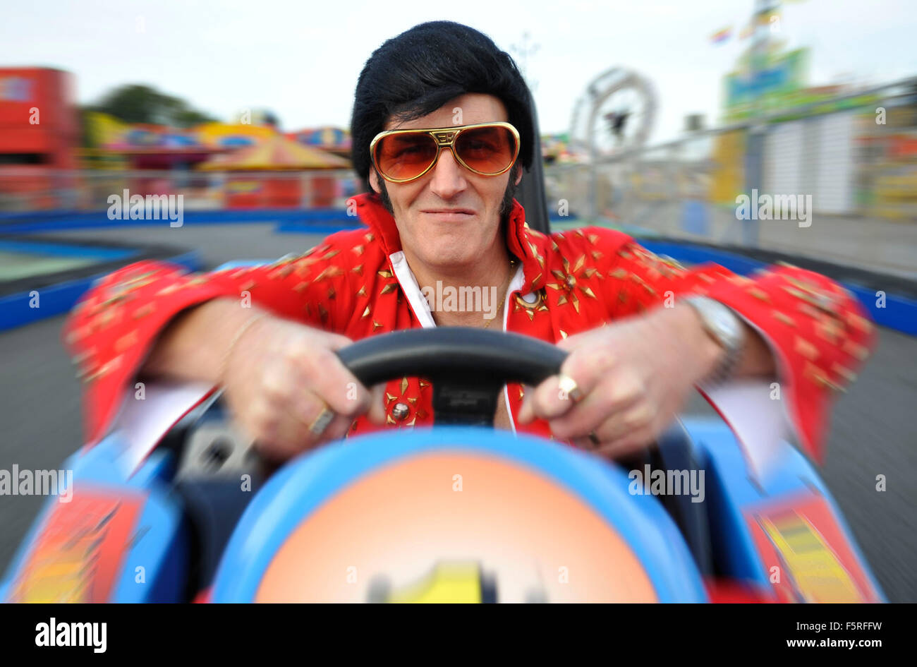 Un sosia di Elvis cavalca un go kart a Coney Beach Parco divertimenti in Porthcawl, nel Galles del Sud durante l'annuale festival di Elvis. Foto Stock