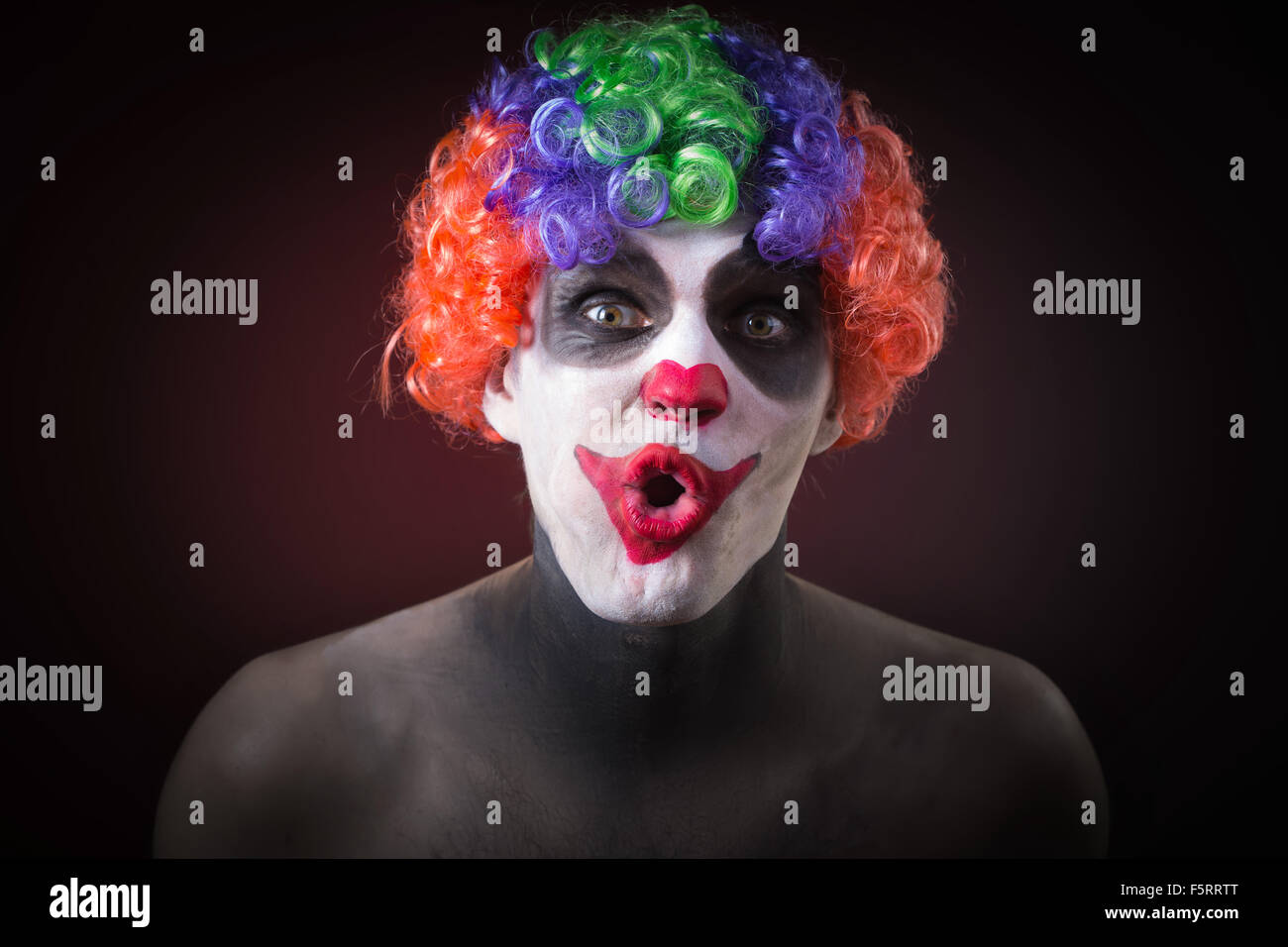 Il male Spooky Clown ritratto su sfondo scuro. uomo espressiva Foto Stock