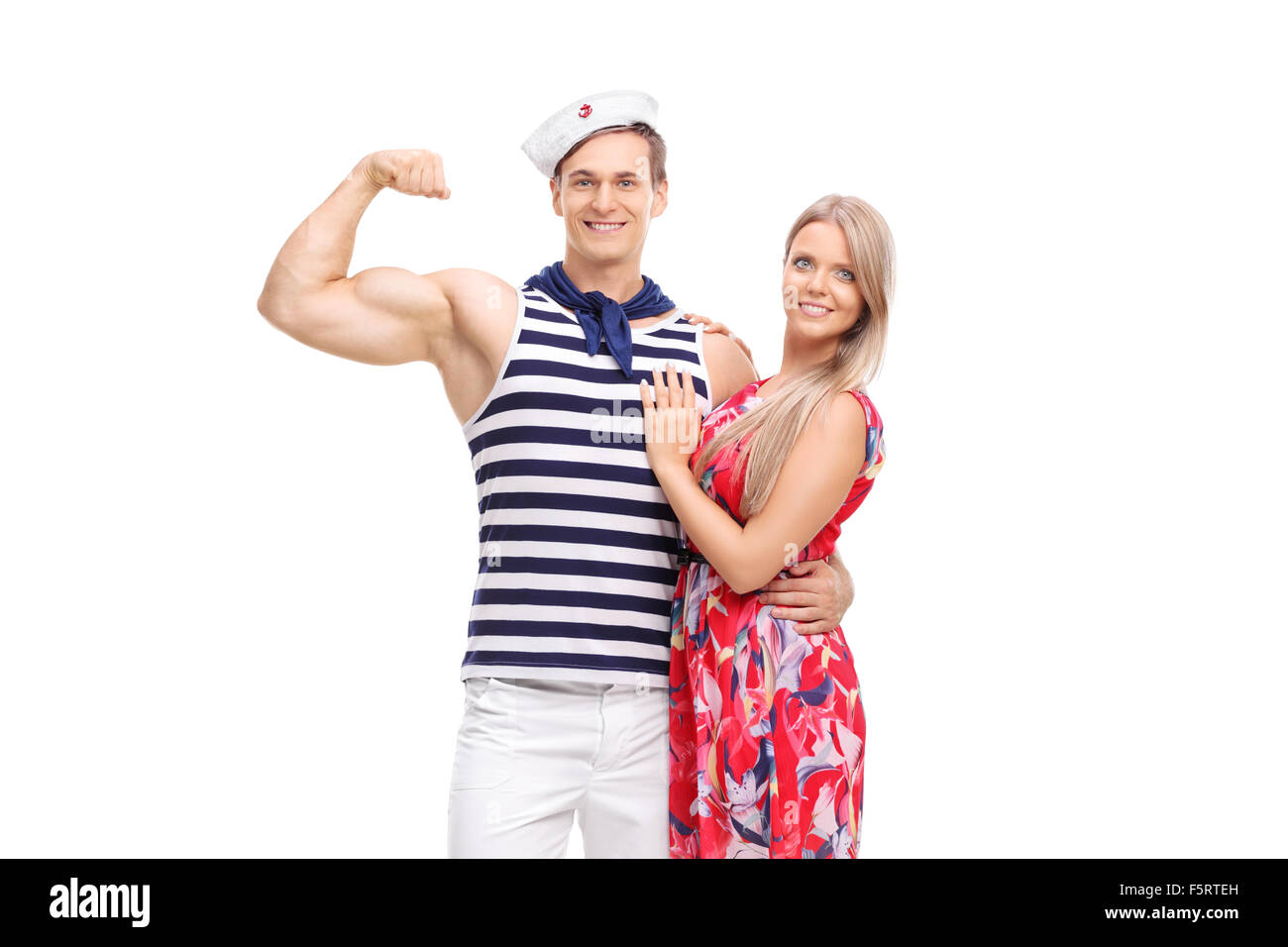 Giovane marinaio flettendo il suo bicipite e in posa con la sua ragazza isolato su sfondo bianco Foto Stock