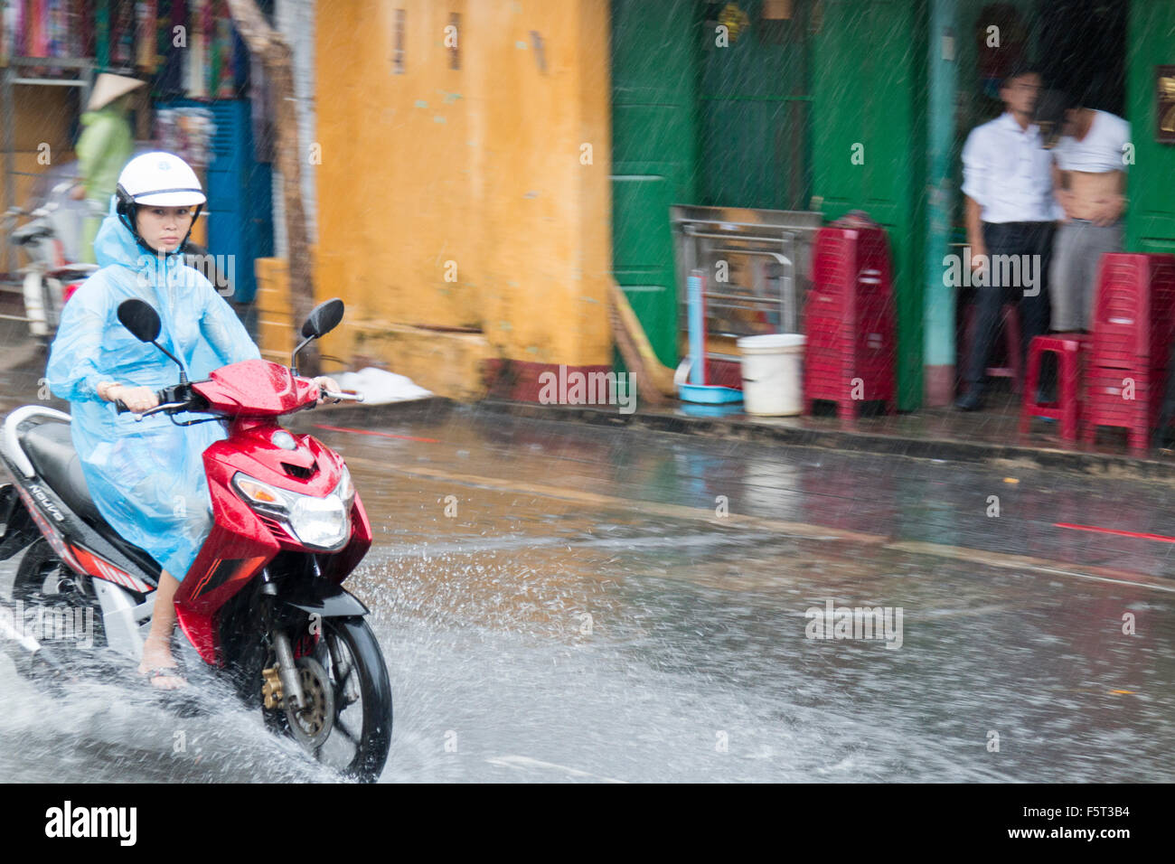 Hoi An old town in Vietnam. Stagione umida e piogge pesanti in città. Signora cavalca la sua bicicletta attraverso strade allagate,Vietnam Foto Stock