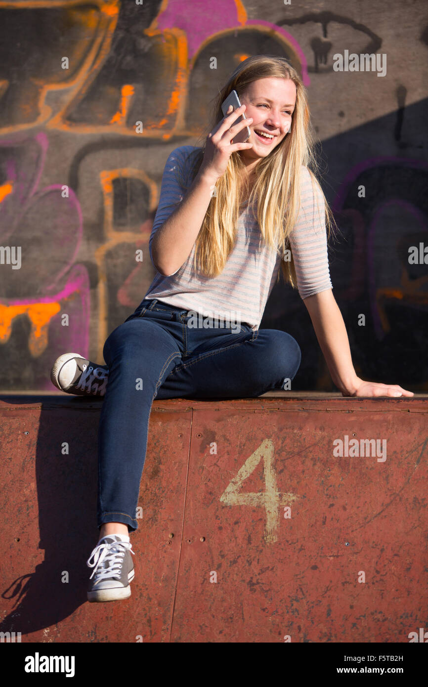 Ragazza adolescente parlando al telefono mobile nel parco giochi Foto Stock