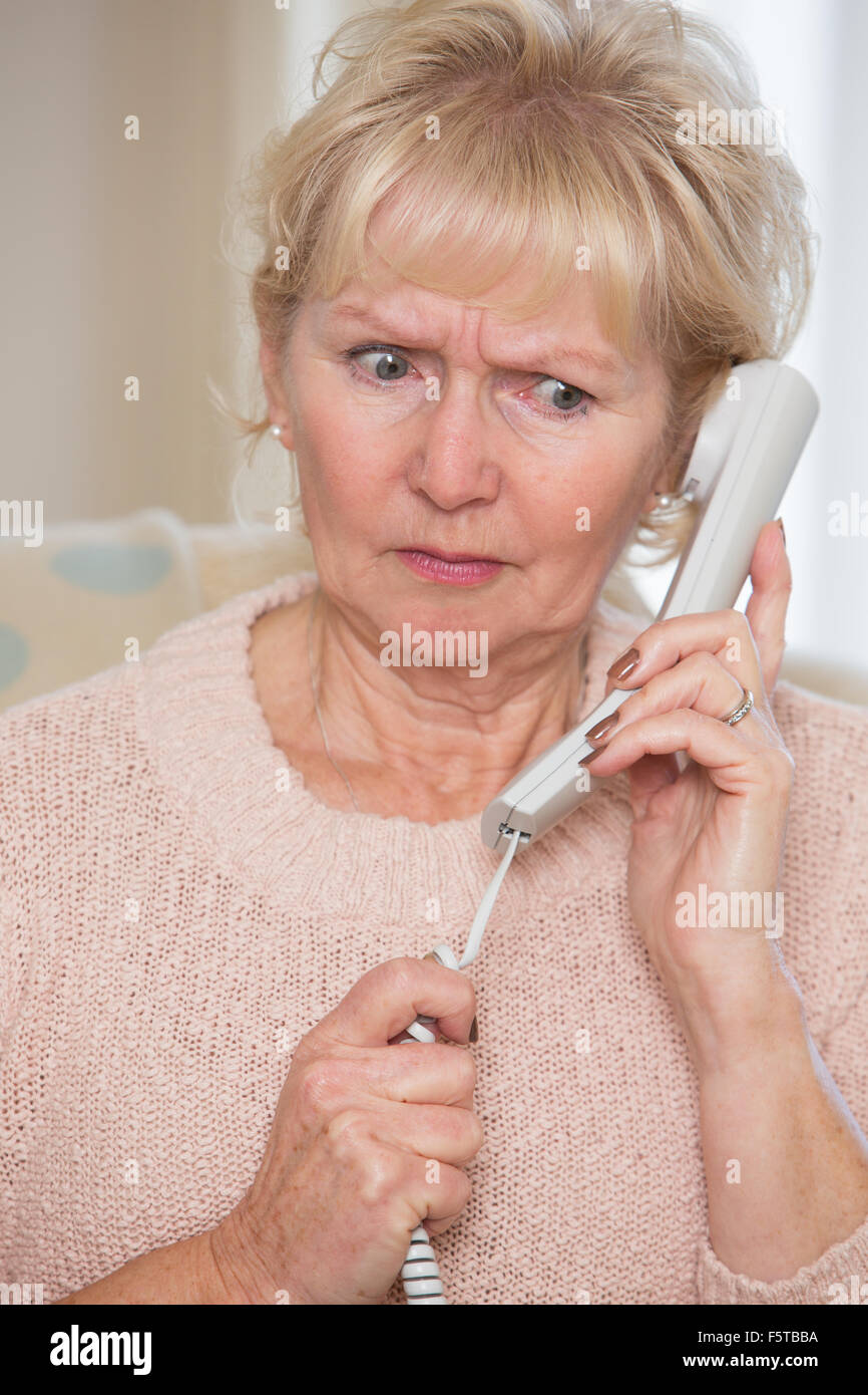 Preoccupato Senior donna rispondendo Telefono in casa Foto Stock