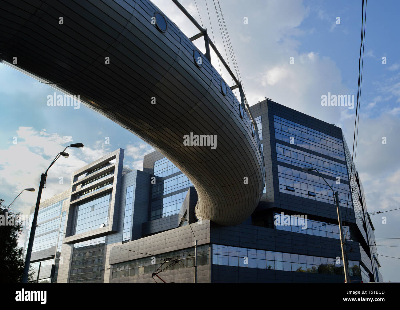 La curva ricoperta in acciaio passerella aerea tra la città di uffici e centro commerciale della città di sviluppo, Bucarest, Romania Foto Stock