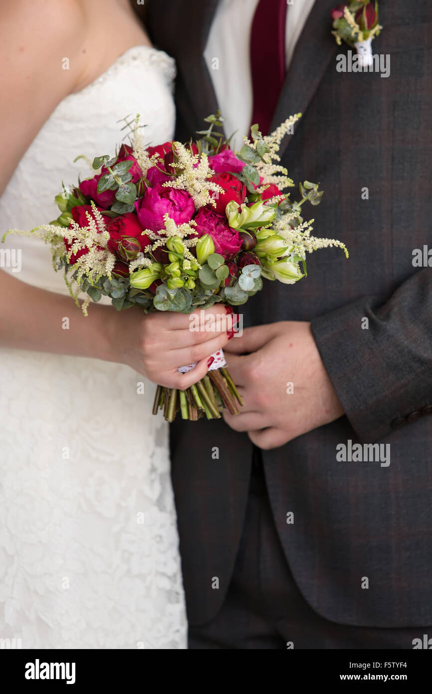 Sposa e lo sposo tenendo in mano un rosso bouquet nuziale Foto Stock