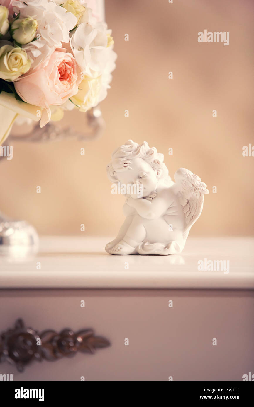 Statua di un angelo e un bouquet nuziale sul comò all'interno Foto Stock