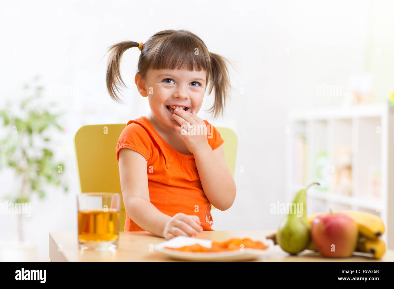 Sorridente ragazza seduta sul tavolo con frutta e succhi di frutta Foto Stock
