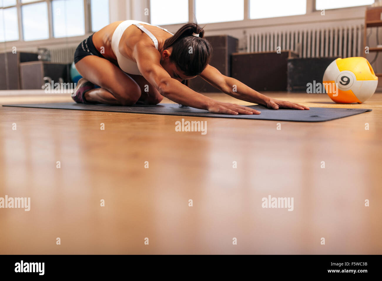 Colpo di una giovane donna fare yoga sul pavimento della palestra. Femmina muscolare facendo stretching allenamento presso un club salute. Foto Stock