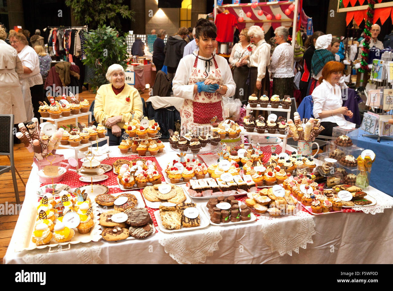 Una torta di vendita e stallholder a un tradizionale inglese il mercato coperto, Buxton, Peak District, DERBYSHIRE REGNO UNITO Inghilterra Foto Stock