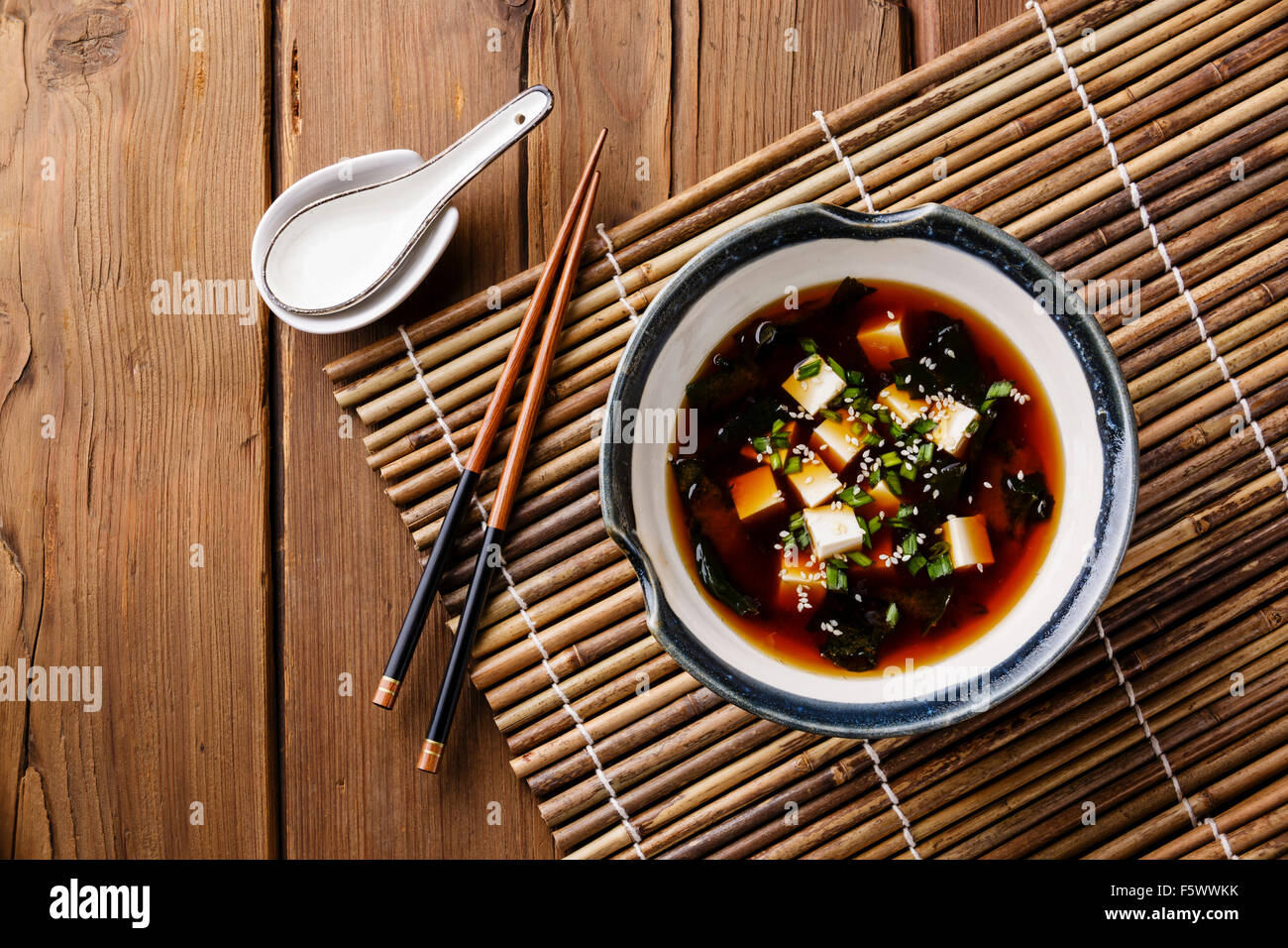 Zuppa di miso con tofu, alghe e sesamo in vaso su sfondo di legno Foto Stock