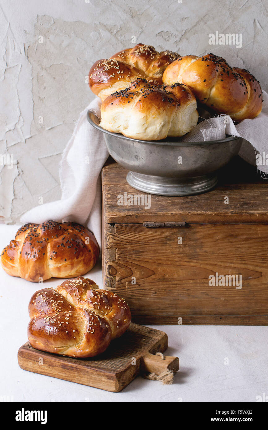 Cumulo di sweet round sabbath challah pane con il bianco e nero di semi di sesamo in metallo vintage ciotola di legno sul petto e sulle piccole c Foto Stock