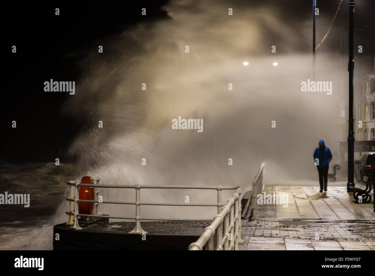 Grandi onde percosse Aberystwyth promenade come uomo in maniera restrittiva manca sempre imbevuto di una grande onda a Aberystwyth Wales UK Foto Stock
