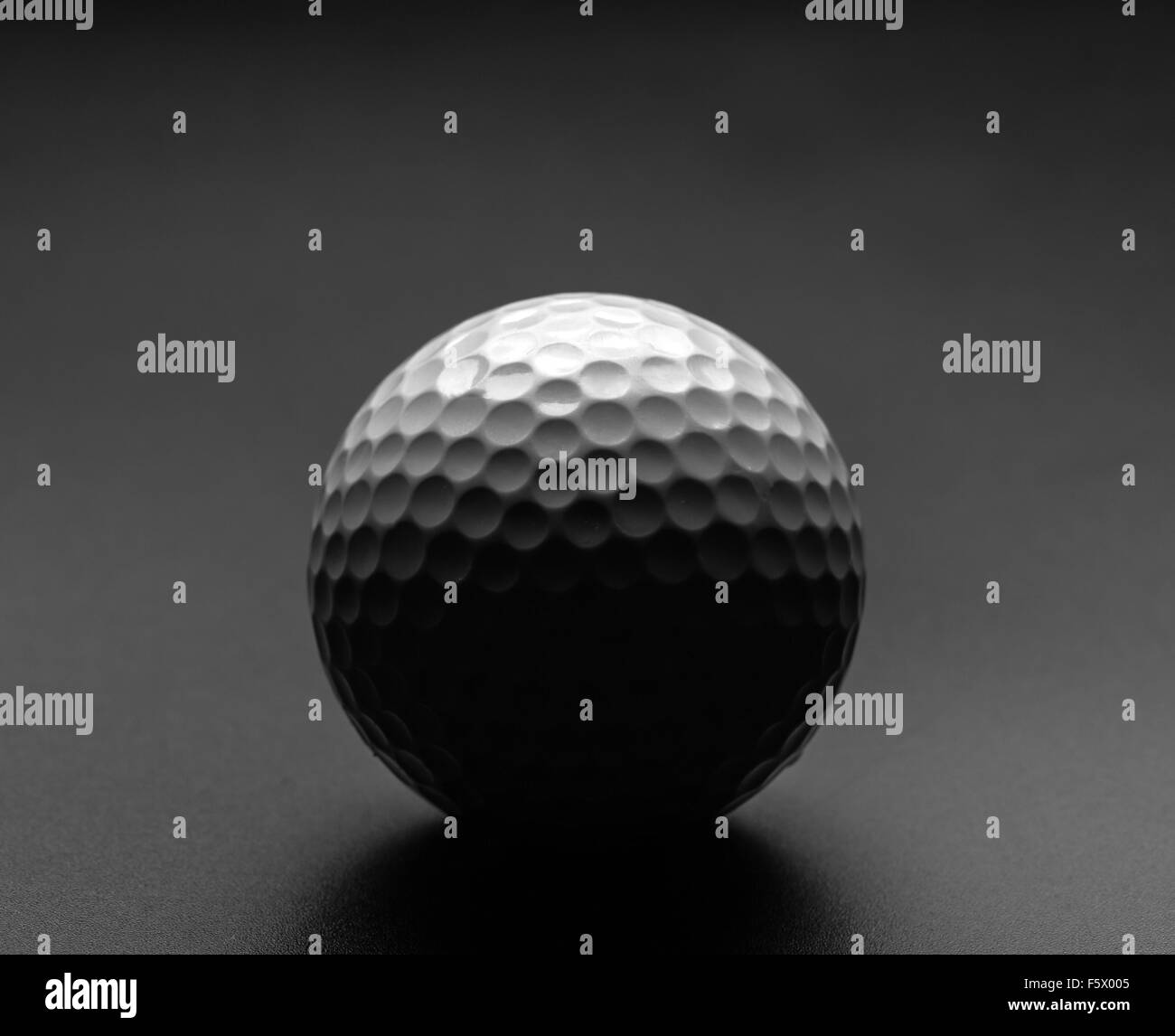 La pallina da golf con grande ombra su sfondo grigio Foto Stock