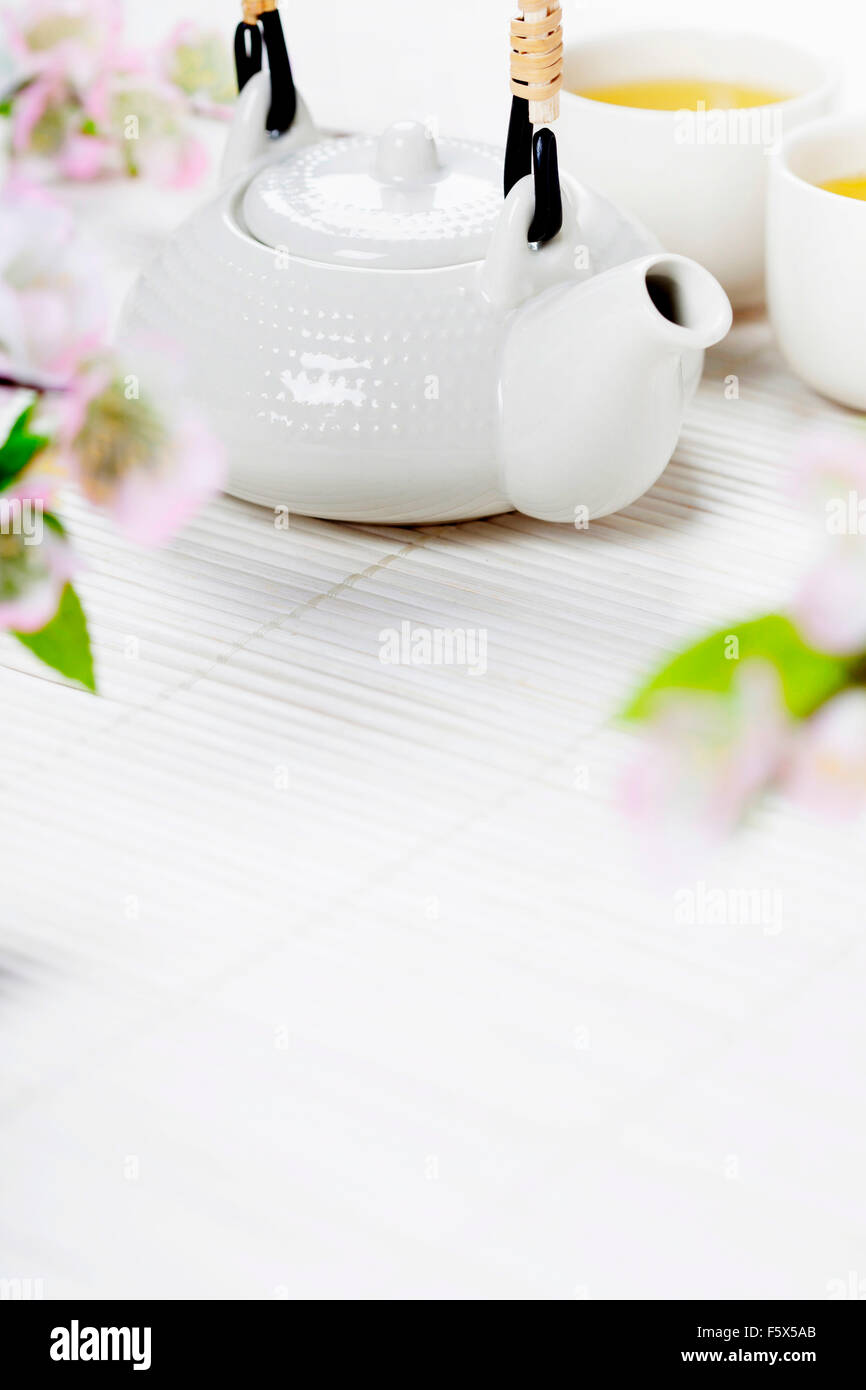 Il cinese Set per il tè e il ramo sakura sul tappetino di bambù Foto Stock