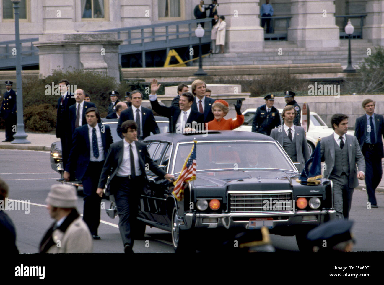 Washington, DC. Stati Uniti d'America 20 gennaio 1981 il Presidente Ronald Reagan e la First Lady Nancy Reagan stand up attraverso il tettuccio della loro limousine salutando la folla rivestimento i marciapiedi del Campidoglio come partono per l'inizio della loro Parata inaugurale. Gli agenti dal servizio segreto presidenziale dettaglio protettivo a piedi lungo il lato delle limousine. Questo è considerato un alto onore per i membri degli Stati Uniti il servizio segreto per raggiungere a piedi tutto il percorso di parata. Alcuni di questi agenti camminava anche lungo il Presidente Reagan scrigno come restituito al Campidoglio lungo questo stesso percorso per il suo funerale. Foto Stock