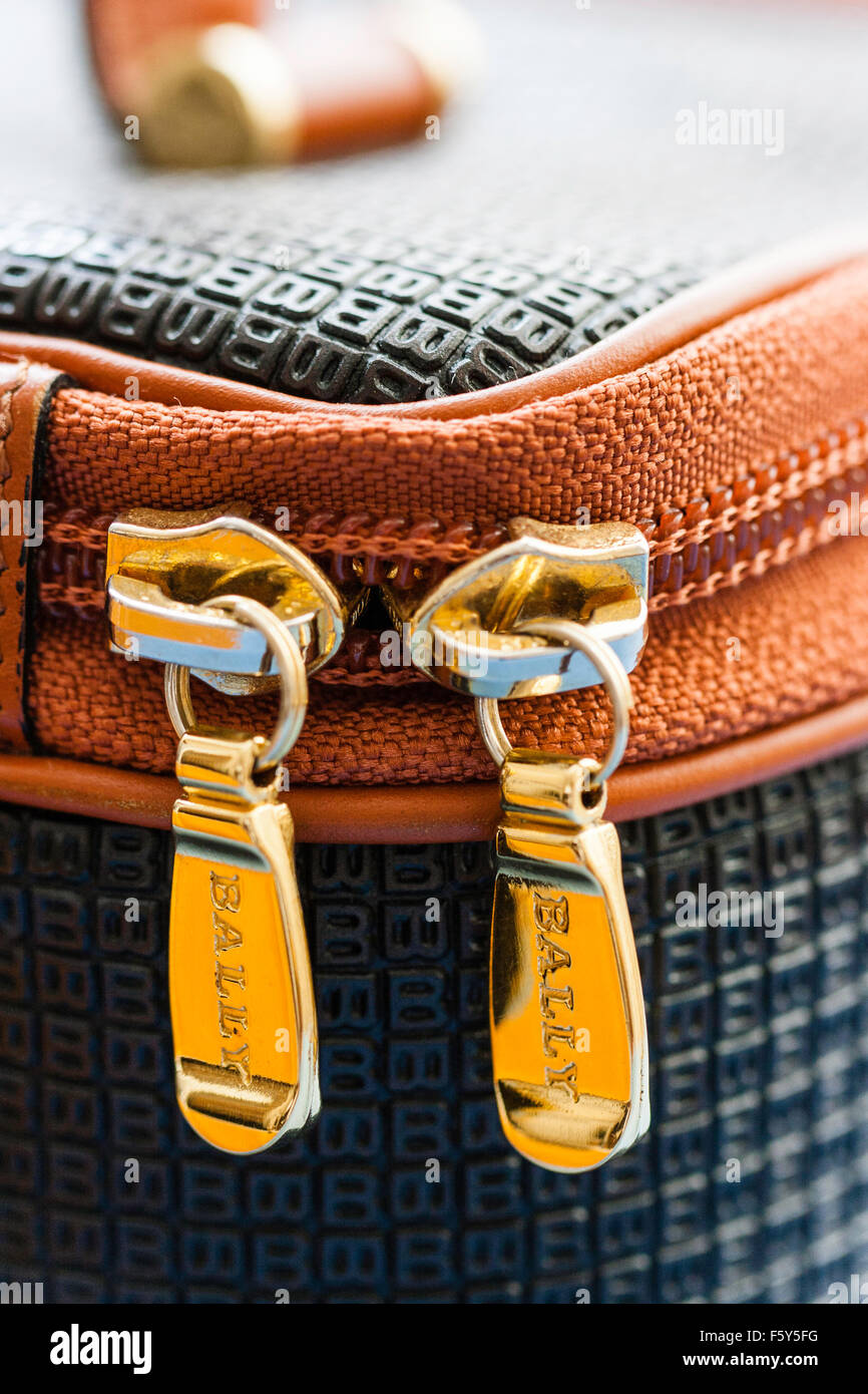 In prossimità delle teste di cerniera lampo su Bally borsa alla moda. Color oro con chiusure lampo di 'bally' il nome di marca sul dito tira. Foto Stock