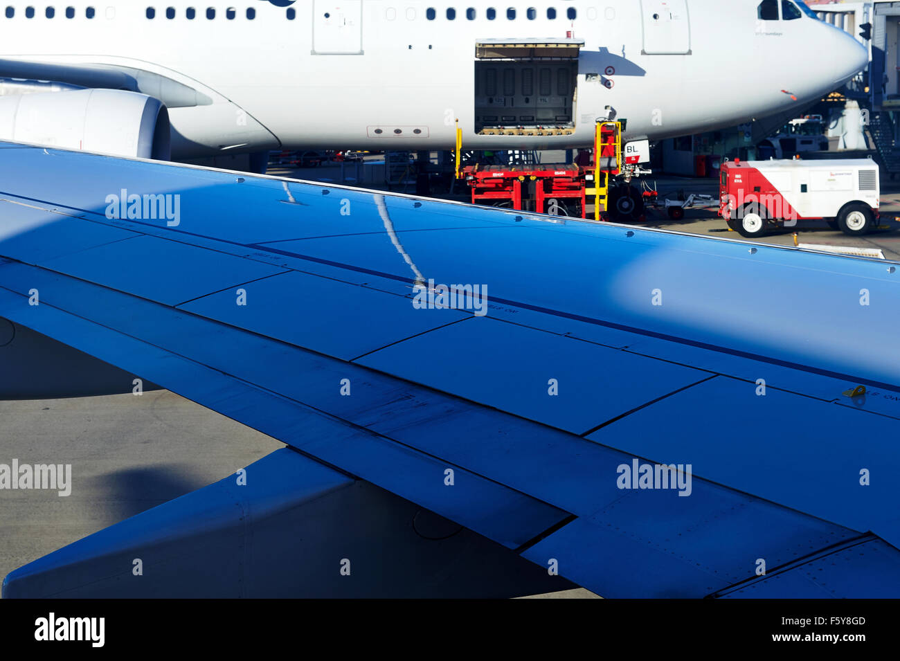 Close up di Boeing 737-800 ala con un altro Boeing 737-800 in background con una gru di carico in posizione. Foto Stock