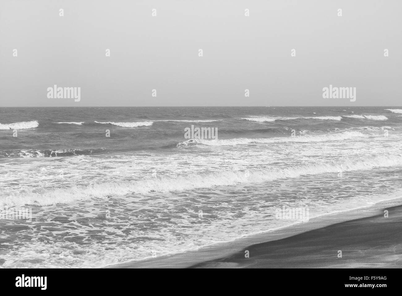 Schiumato in arrivo onde del mare su una spiaggia tropicale. Queste onde impetuose lasciare profili curvi sulla spiaggia. Immagine in bianco e nero. Foto Stock
