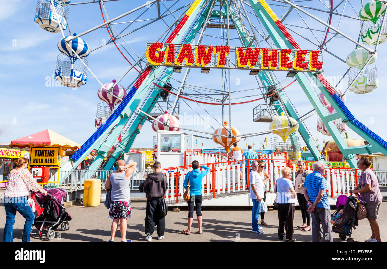 I vacanzieri la visione di una stazione balneare fairground ride. Le persone in vacanza dalla ruota gigante a Pleasure Beach, Skegness, Lincolnshire, England, Regno Unito Foto Stock