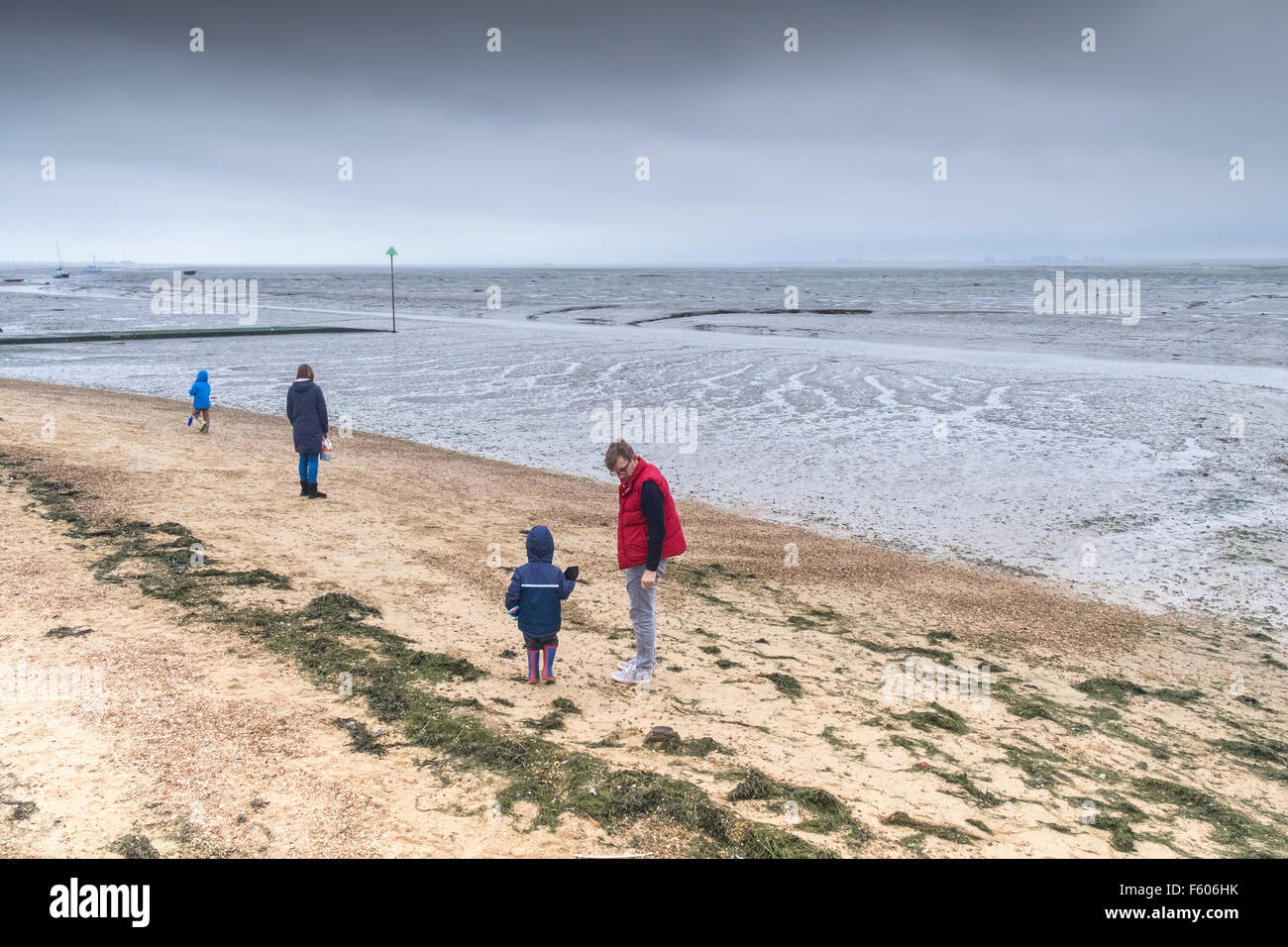 Una famiglia di brave il freddo sulla campana Wharf beach a Leigh on Sea, Essex. Foto Stock