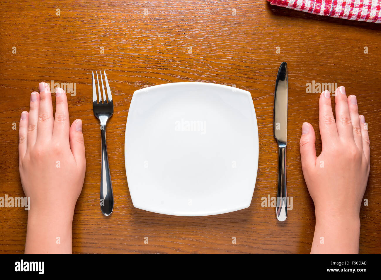 Mani femminili vicino a piastra vuota sul tavolo Foto Stock