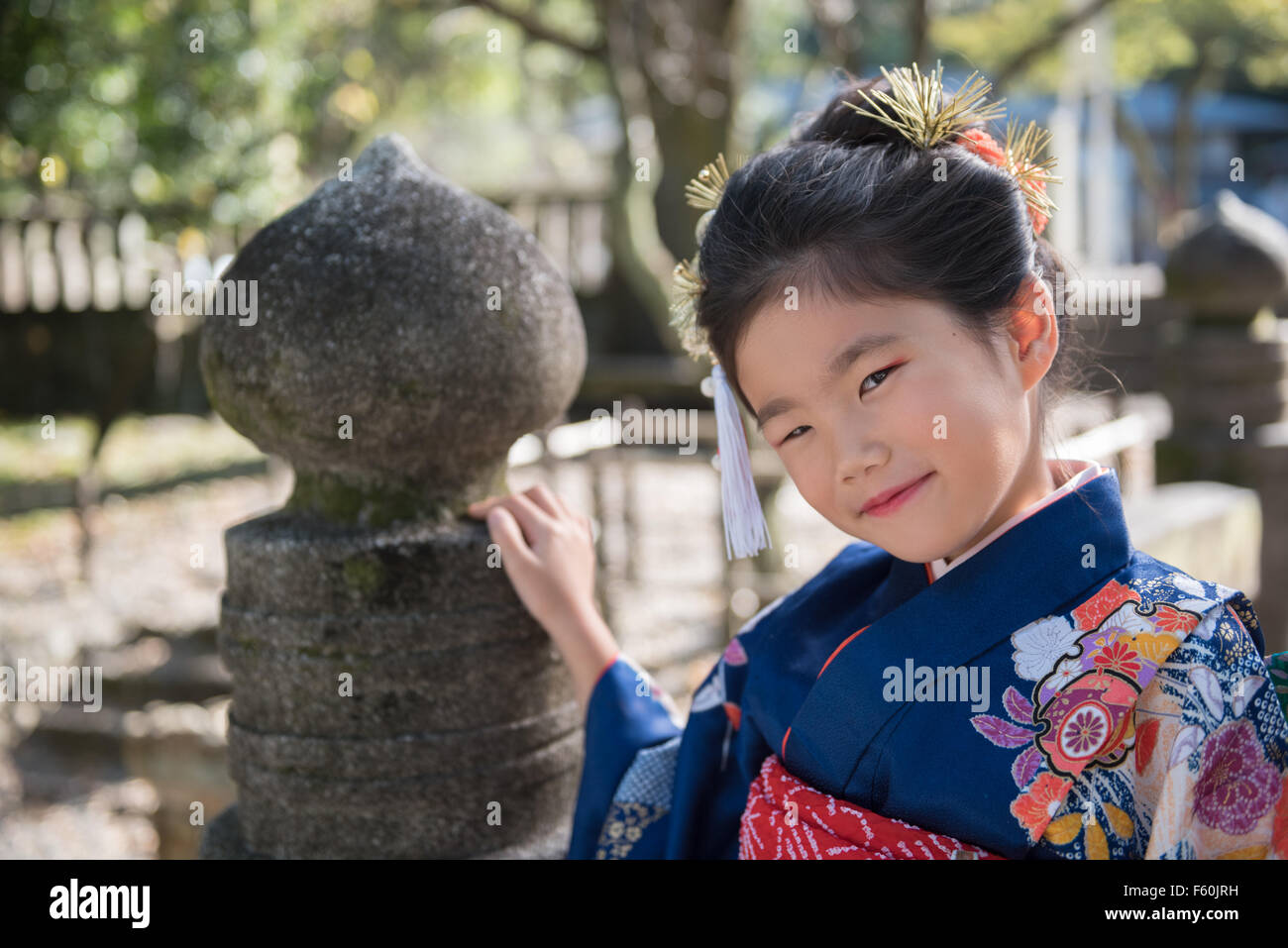 Una giovane ragazza giapponese in un kimono all'aperto presso un santuario. Foto Stock