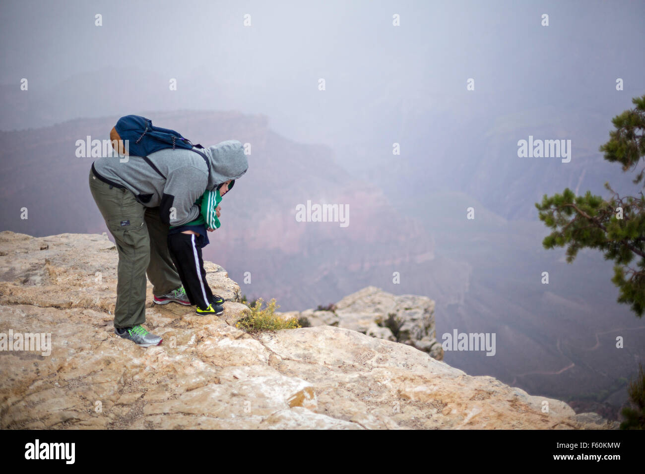 Parco Nazionale del Grand Canyon, Arizona - un uomo detiene un ragazzo come essi peer oltre il bordo del bordo Sud del Grand Canyon. Foto Stock