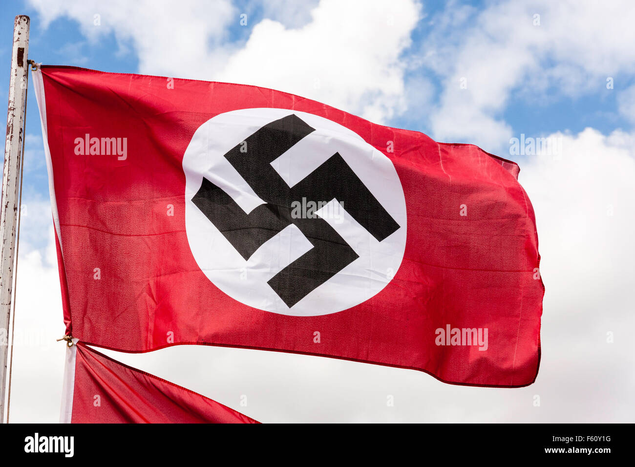 La seconda guerra mondiale la rievocazione. Il tedesco rosso, bianco e nero nazista svastica bandiera. Che fluttua nel vento contro il cielo blu con nuvole bianche. Foto Stock