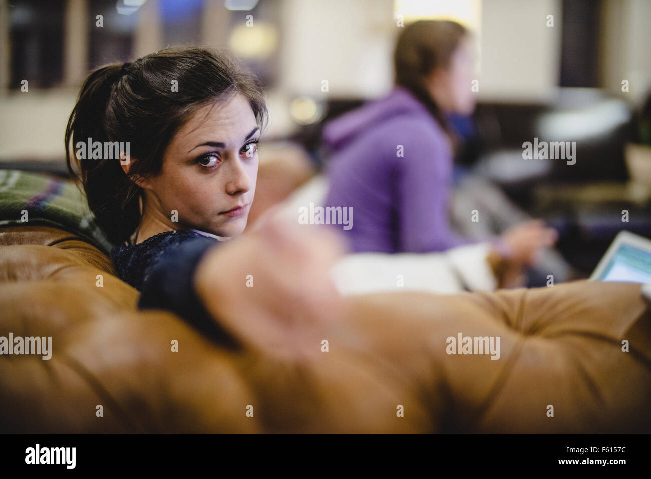 Una giovane donna puntando verso la telecamera con sua sorella e cane in background Foto Stock