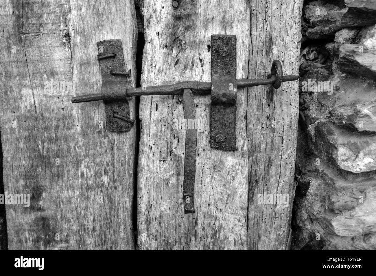 Ferro vecchio gancio di chiusura sulla porta di legno con parete di pietra Foto Stock