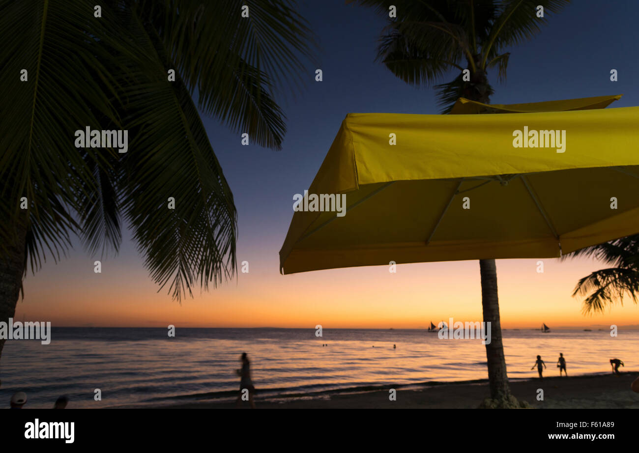 Ombrellone giallo a una bellissima spiaggia tropicale durante il tramonto Foto Stock