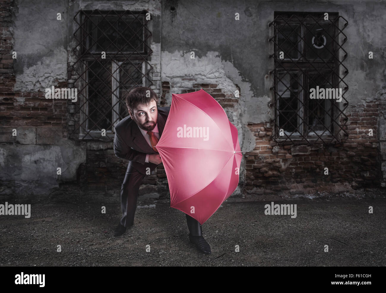 Spaventata imprenditore protegge se stesso con ombrellone Foto Stock