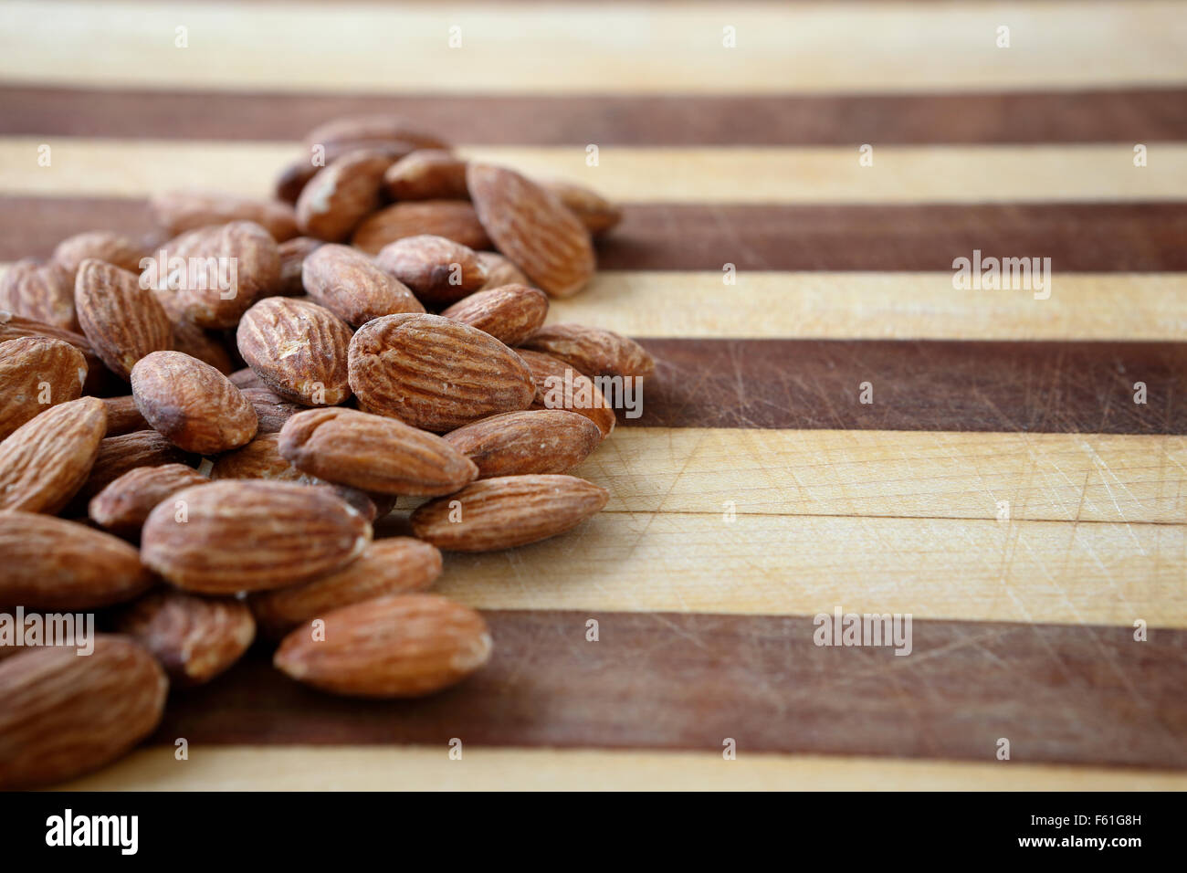 Un mazzetto di mandorle su un tagliere pronto a diventare parte di un sano nutriente merenda. Foto Stock