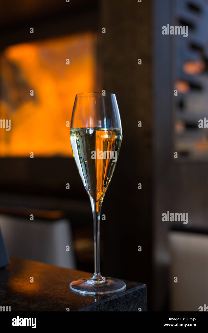 Vista al livello degli occhi del vino spumante in una barra scura ambiente con arancione e blu navy accenti. Foto Stock
