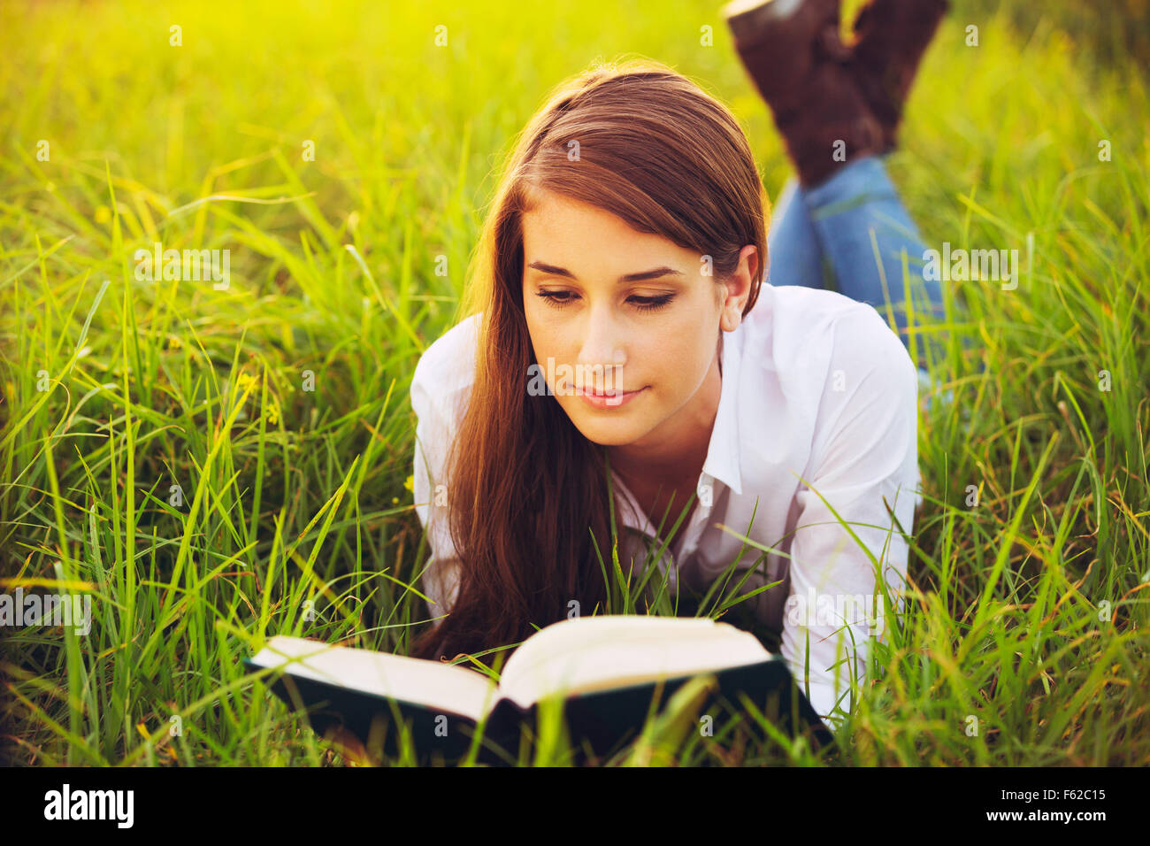 Giovane donna godendo un libro lettura all'aperto Foto Stock
