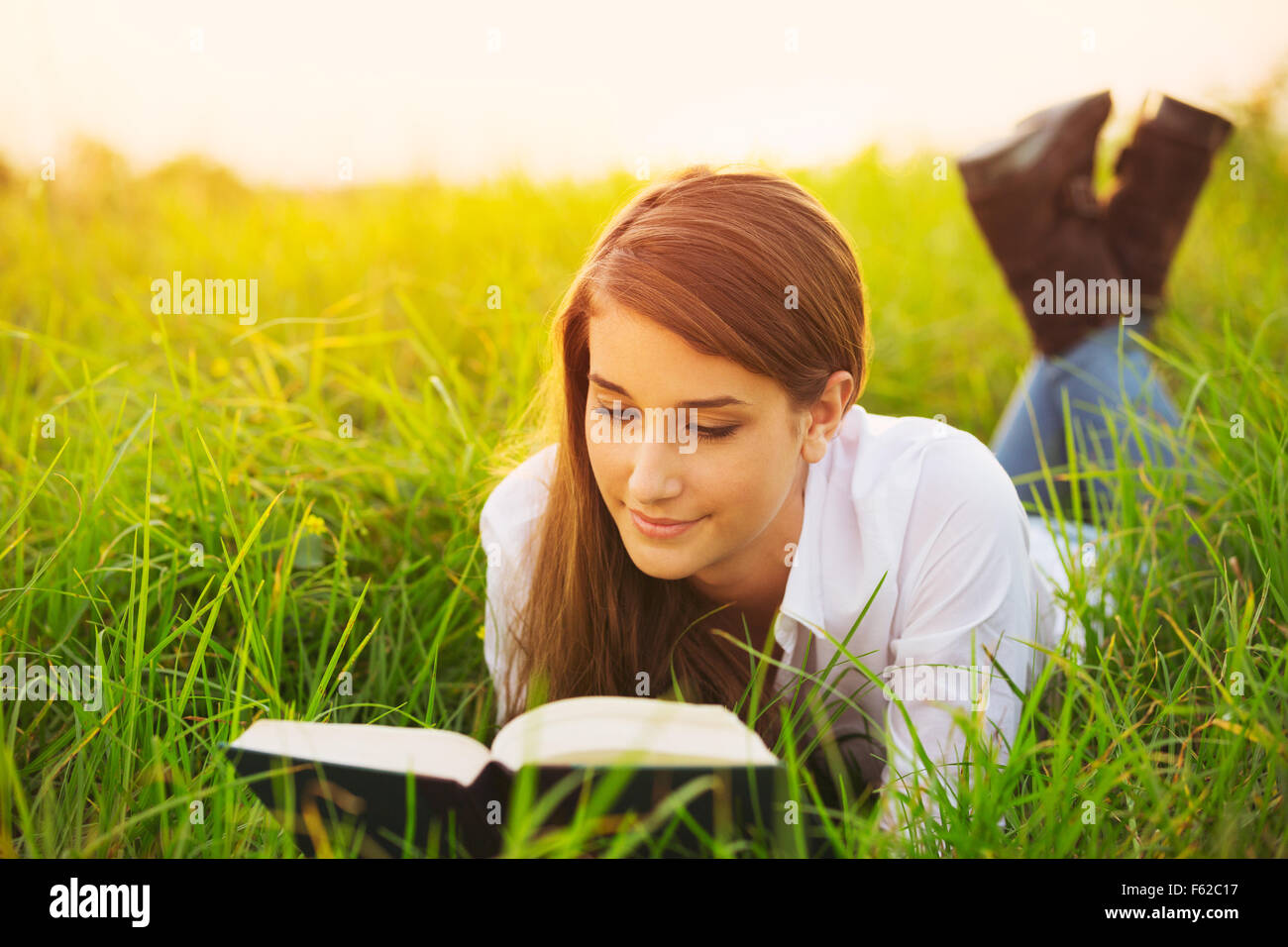 Giovane donna godendo un libro lettura all'aperto Foto Stock