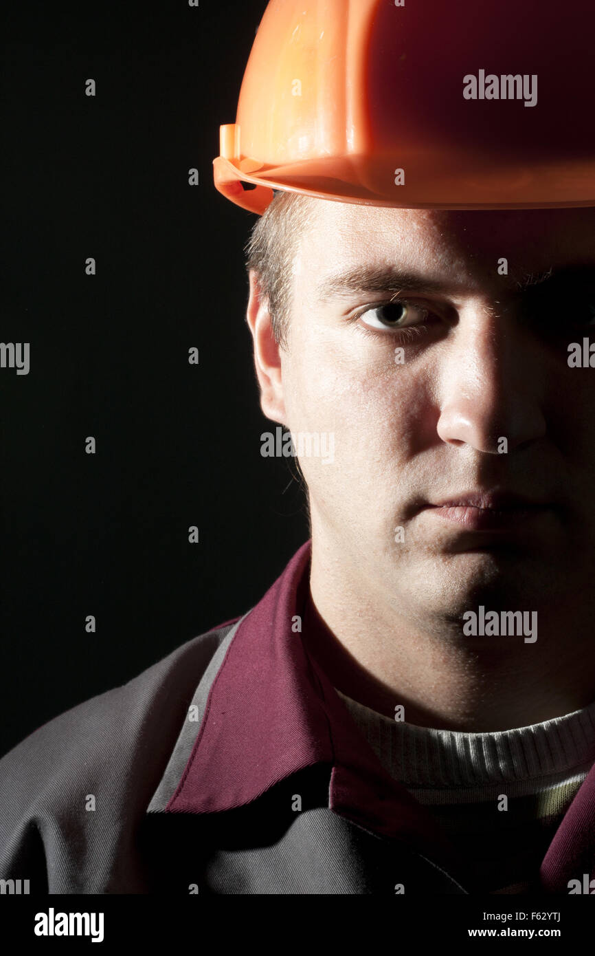 Ritratto di grave builder in abbigliamento da lavoro e casco Foto Stock