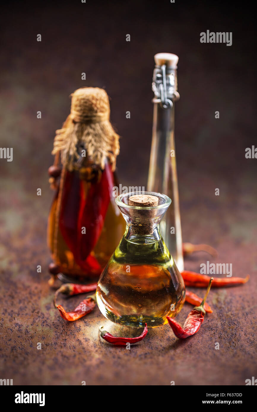 Olio aromatizzato al peperoncino in diverse bottiglie di vetro Foto Stock