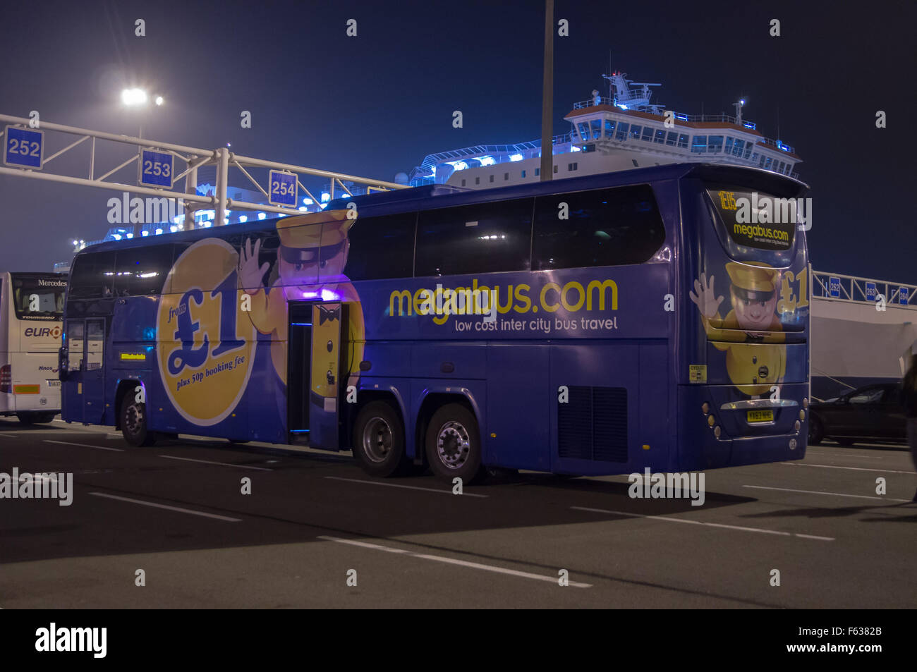 Un autobus internazionale Megabus con un poster che fa pubblicità a tariffe £1 al porto dei traghetti di Calais di notte, Nord-Pas-de Calais, Francia Hauts de France Foto Stock