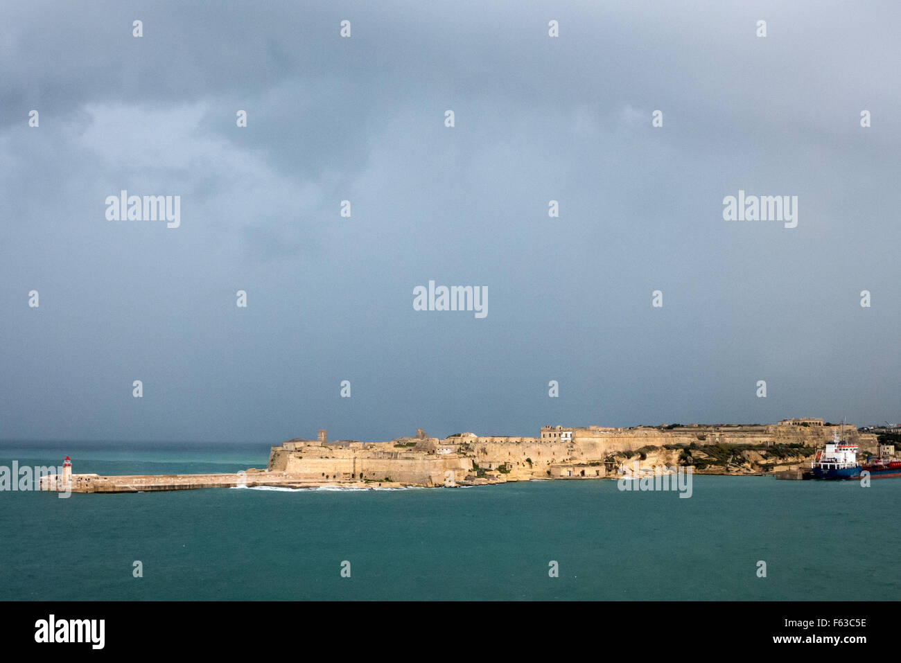 La luce del sole in un giorno di tempesta oltre la parete del porto di La Valletta a Malta. Foto Stock