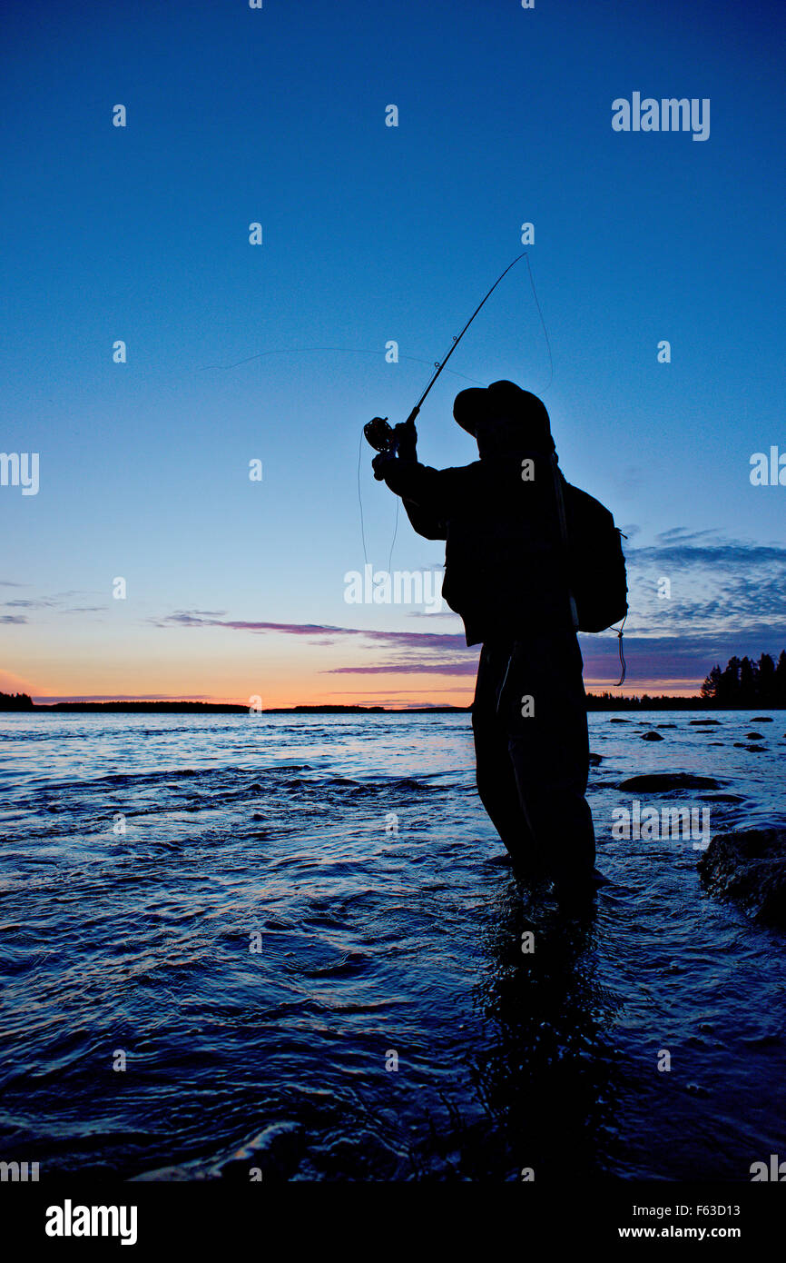 Fly fisherman cercando di catturare la trota fario. Lentua rapids, Kuhmo, in Finlandia. Foto Stock