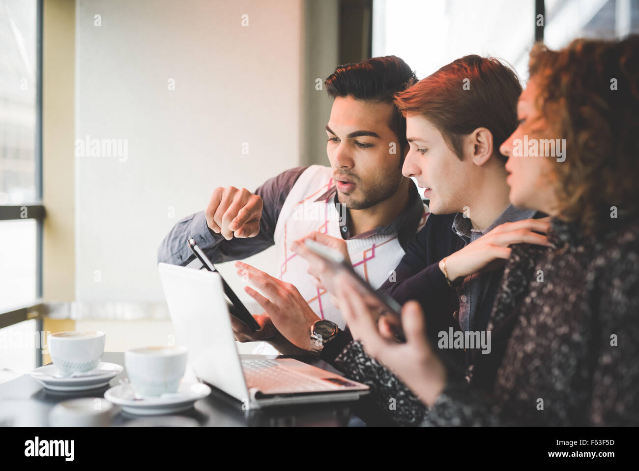 Gruppo di multirazziale business chi lavora seduto in un bar sorseggiando un caffè, collegato con dispositivi tecnologici come smartphone e tablet pc portatile - tecnologia, lavorare, la concezione di business Foto Stock